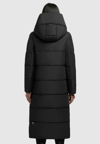 Schwarze Pufferjacke mit langem Design, großer Kapuze und gestepptem Material. Mit einem seitlichen Reißverschluss-Taschen in der Nähe des Saums.