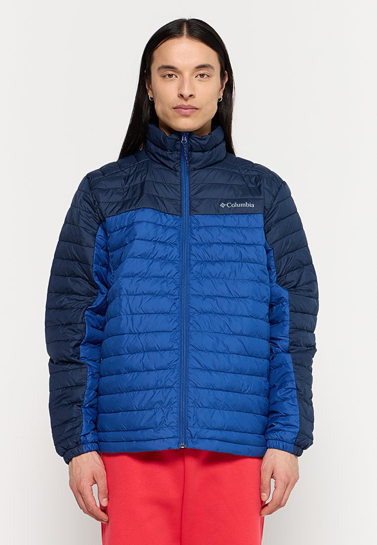 Chaqueta puffer azul con acentos en azul oscuro, que presenta un cuello alto y cierre de cremallera. Diseño ligero y acolchado con detalles del logotipo de Columbia.