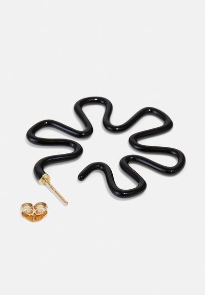 Schwarze, wellenförmige Ohrringe mit glänzender Oberfläche und goldfarbener Stiftfassung, begleitet von einem kleinen goldenen, runden Ohrring.