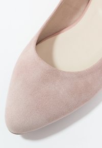 Chaussure plate en daim rose à bout pointu avec une surface lisse et texturée, et un design à découpe basse, dotée d'une doublure intérieure beige.