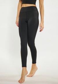 Fekete leggings rugalmas anyagból, magas derékkal, elegáns kivitelezéssel és finom varrási részletekkel.