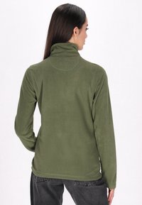 Pullover in pile verde con colletto alto e maniche lunghe. Tessuto morbido, design aderente e cuciture piatte. La vista dal retro mette in evidenza la semplicità.