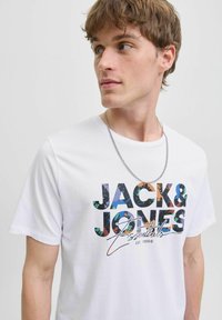 Weißes Baumwoll-T-Shirt mit mehrfarbigem Aufdruck "JACK & JONES Essentials" und einem subtilen grafischen Muster, getragen mit einer silbernen Kettenhalskette.
