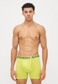 Νεον κίτρινες σορτς μποξέρ με φαρδύ μπλε λάστιχο "BJÖRN BORG", φτιαγμένες από ελαστικό υλικό, με εφαρμοστή σχεδίαση και απαλό υφή.