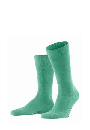 Grüne Baumwollsocken mit Rippbund und glatter Textur, ausgestattet mit einem nahtlosen Zehenbereich und subtiler Markenkennzeichnung an der Sohle.