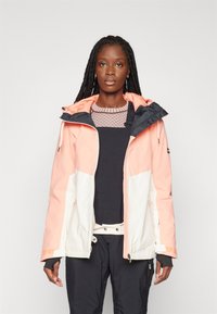 Giacca da donna con un design a blocchi di colore rosa e bianco, con cappuccio, tasche con zip e texture morbida e liscia.