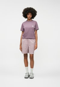 Μωβ βαμβακερό μπλουζάκι με τσέπη στο στήθος, συνδυασμένο με ανοιχτό ροζ υφασμάτινες βερμούδες και γκρίζες σαγιονάρες. Απαλή υφή, άνετη εφαρμογή και χαλαρό στυλ.