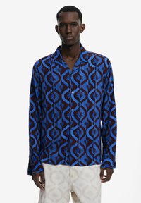 Blue and brown patterned long-sleeve shirt with a button-up design, featuring swirling motifs and small sunburst accents.