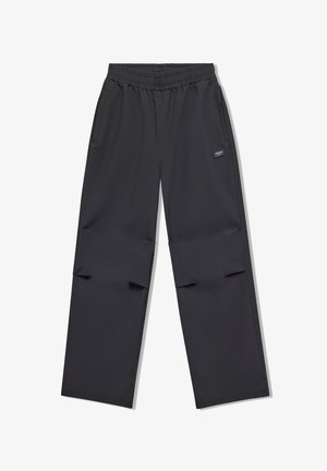 Pantalones negros de pierna recta con cintura elástica, bolsillos laterales y una pequeña etiqueta rectangular de la marca en el muslo derecho.
