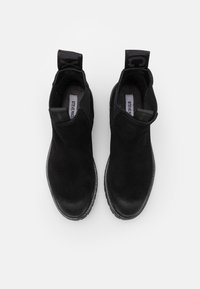 Paire de bottines en daim noir avec languettes de tirage et semelles intérieures rembourrées, vues de dessus sur fond blanc.