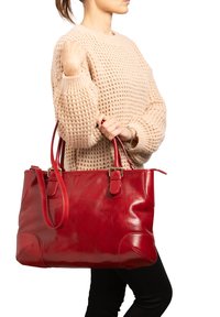 Borsa tote rossa in pelle con una texture liscia, manici doppi e un design elegante. Presenta cuciture evidenti e un interno spazioso.