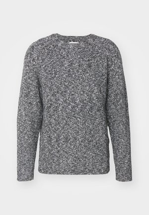 Pull en tricot gris et noir avec un col rond, des manches longues et des poignets côtelés, présentant un tissu texturé et à motifs.