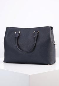 Borsa a tracolla sintetica blu navy con due manici, texture liscia, dettagli hardware tono oro e forma rettangolare strutturata.