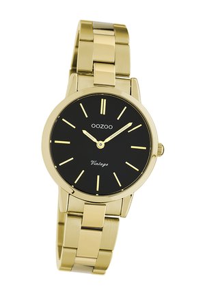 Montre-bracelet en métal doré avec un cadran noir, dotée d'un boîtier rond, d'index horaires fins et d'un bracelet texturé. La marque sur le cadran indique "OOZOO Vintage."