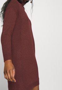 Abito lavorato a maglia, a maniche lunghe, color bordeaux con collo alto; silhouette aderente; texture a costine sulle maniche e sull'orlo; lunghezza fino alla coscia.