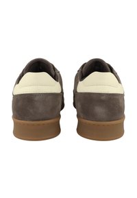 Grå mockasneakers med en gräddvit läderdetalj vid hälen, gummisula och sydda detaljer på baksidan.