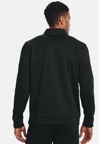 Pullover nero a maniche lunghe con colletto, caratterizzato da una texture liscia e un design aderente. Include un fondo orlato e maniche con polsini.