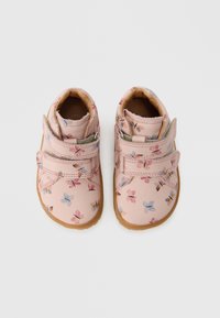 Rozā bērnu apavi ar ziedu rakstiem, dubultām Velcro aizdari un brūnu gumijas zolīti, ar gludu tekstūru un apaļu formu.