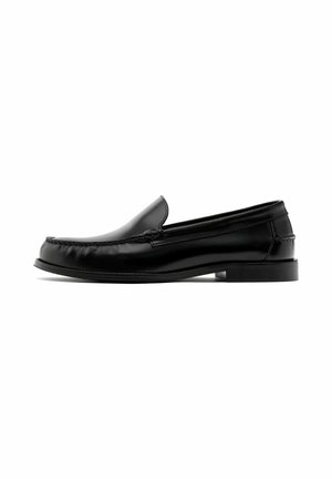 Mocassin à enfiler en cuir noir avec bout arrondi, petit talon et détails cousus dans le style mocassin sur les côtés et à l'avant.