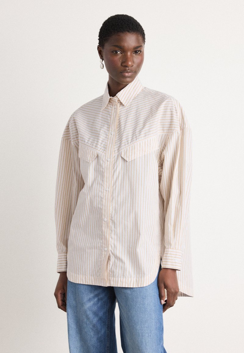 Camicia a righe botton-up in crema e arancione chiaro, con due tasche sul petto e una vestibilità rilassata con maniche lunghe. Tessuto liscio e leggero.