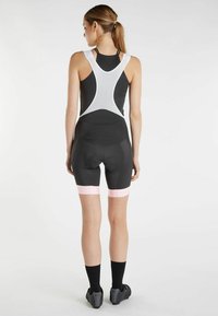 Completo da ciclismo nero con top senza maniche e schiena in rete bianca, dettagli rosa sui pantaloni che presentano una zona imbottita per il sedile.