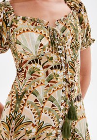 Kleid mit floralem Muster und kurzen Puffärmeln in grün, braun und cremefarben, mit einer Knopfleiste und Quastenakzenten an der Taille.
