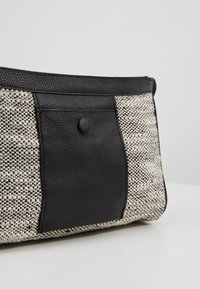 Piccola borsetta a forma rettangolare con tasca centrale in pelle nera e rifiniture, fiancheggiata da pannelli in tessuto intrecciato crema e nero.
