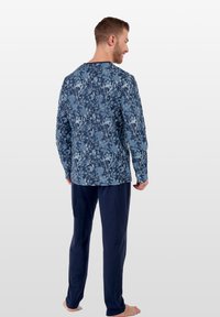 Pitkähihaiset pyjamapaita sinisellä kukkakuviolla, yhdistettynä laivastonsinisiin housuihin. Pehmeä kangas, rento malli, pyöreä kaula-aukko.