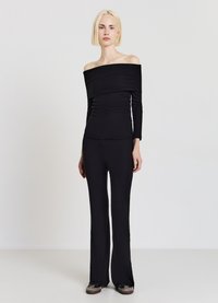 Schwarzes, geripptes, schulterfreies Oberteil, kombiniert mit passenden, gerippten, ausgestellten Hosen. Baumwollmischgewebe mit körperbetontem Schnitt und strukturierter Oberfläche.