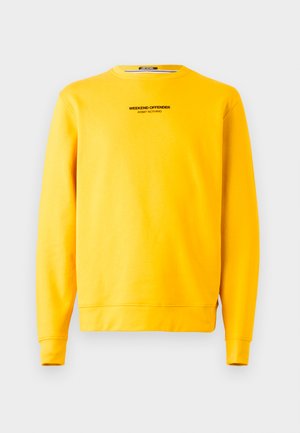 Žlutá mikina vyrobená z měkké látky, s kulatým výstřihem a dlouhými rukávy. Na přední straně je vytištěn nápis "WEEKEND OFFENDER" černou barvou.