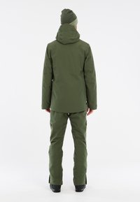 Grüne Winterjacke mit Kapuze, kombiniert mit passenden Hosen. Glattes, wasserabweisendes Material; minimalistisches Design; taillierte Silhouette; Reißverschlüsse an den Hosen.