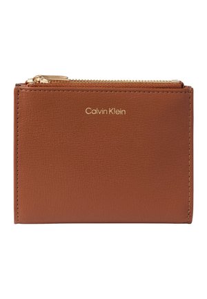 Portefeuille en cuir marron avec logo Calvin Klein doré et une fermeture éclair dorée sur le dessus.