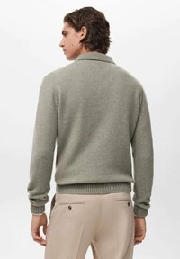 Maglione lavorato a maglia verde chiaro con collo e polsini a costine, caratterizzato da una vestibilità rilassata. Il tessuto testurizzato si abbina bene a pantaloni beige.