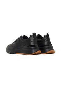 Zwarte leren sneakers met een gemarmerde afwerking, voorzien van een dikke zwarte zool en een bruine rubberen buitenzool. Eenvoudig, functioneel ontwerp.