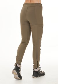 Olivgröna, stretchiga utomhusbyxor med tapered passform, knä sömmar, sidofickor och svarta detaljer. Bärs med svarta vandringsskor.