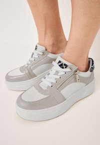Sneakers grigio e bianchi con materiale testurizzato, dotati di una cerniera laterale, punta rotonda e dettagli con stampa leopardata sul colletto.