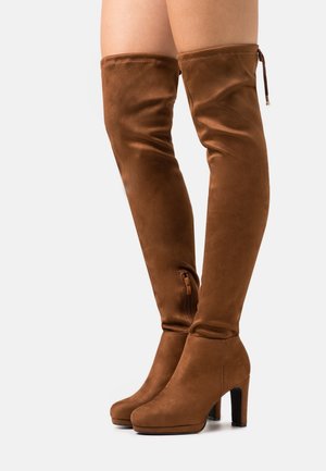 Hnědé semišové kozačky sahající ke kolenům s blokovým podpatkem, se zipem na boku, hladkou texturou a přiléhavým střihem sahajícím až do poloviny stehenní části.