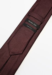 Burgunderfarbige, strukturierte Krawatte aus gewebtem Stoff mit einer spitzen Spitze, versehen mit schwarzen Etiketten, auf denen "Massimo Dutti" und "MADE IN ITALY" steht.