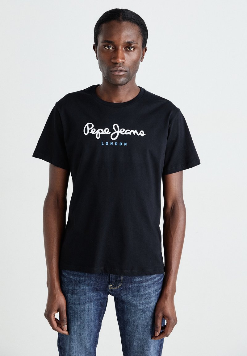Sort bomulds-T-shirt med korte ærmer, udstyret med hvid skriftlogo "Pepe Jeans" og "LONDON" i blå. Båret med blå denim jeans.