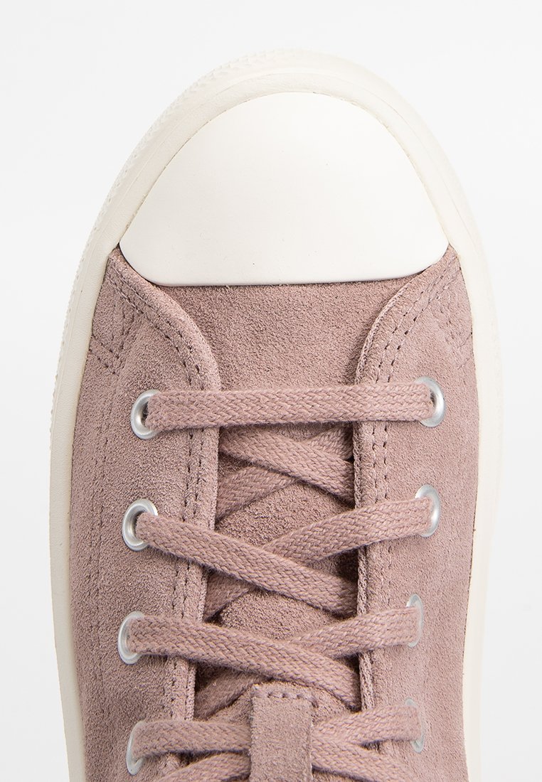 Sneaker in suede rosa chiaro con punta in gomma bianca, dotata di occhielli metallici e lacci piatti. Parte superiore texturizzata e suola liscia.