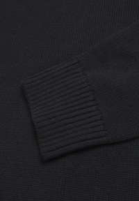 Zwarte gebreide trui detail met een geribbelde manchettextuur. De stof is fijn en glad met een uniform patroon doorheen.