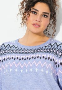 Maglione azzurro chiaro in maglia con una spalla decorata con motivi geometrici in nero, rosa e bianco. Tessuto morbido e scollo rotondo.