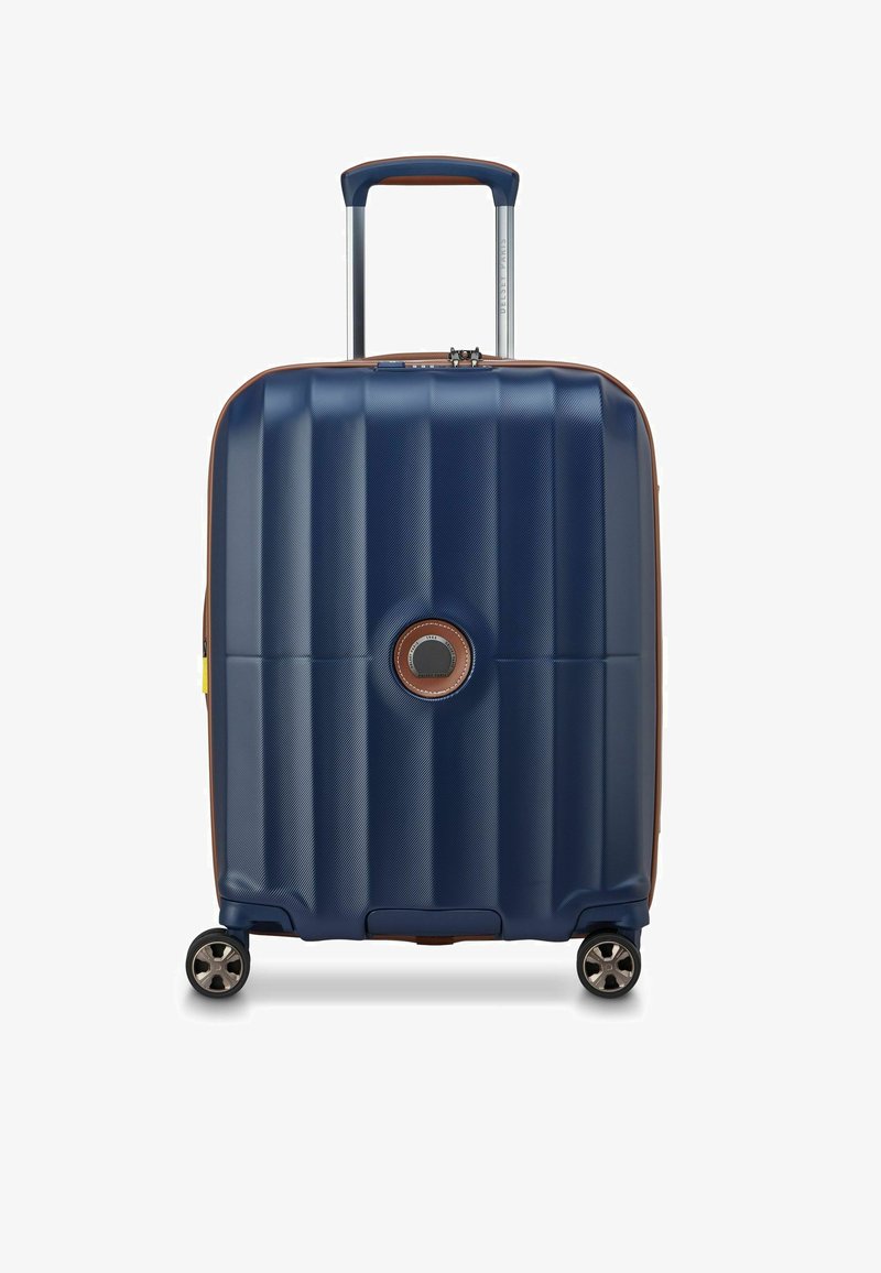 Maleta rígida de color azul marino con un acabado texturizado, detalles en marrón, un asa superior y cuatro ruedas para facilitar la maniobrabilidad.