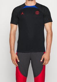 Czarny t-shirt sportowy z niebieskimi akcentami, z czerwonym logo na piersi. Wykonany z materiału odprowadzającego wilgoć, krótki rękaw.