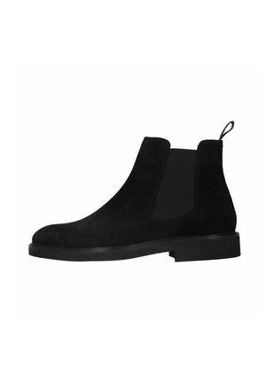 Bottes Chelsea en daim noir avec panneau latéral élastique, languette de tirage au talon et semelle basse empilée, présentées en profil droit sur fond blanc.