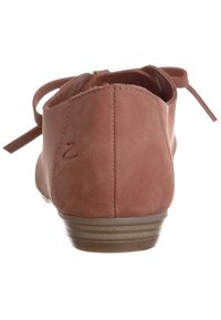 Zadní pohled na růžovou koženou balerínu s kulatou špičkou, nízkým podpatkem, minimálním prošíváním a zavazovacími tkaničkami vzadu pro úpravu velikosti.