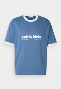 Blue cotton t-shirt with white ribbed collar and sleeve cuffs. Front features "calvin klein" logo and "West 39th Street New York City" text.