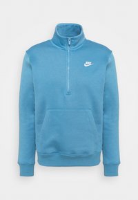 Sudadera de Nike de color azul claro con cuello alzado con cremallera, bolsillo frontal y puños acanalados. Presenta un pequeño logo blanco en el pecho.
