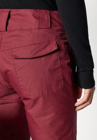 Bordeaux cargo broek van een gladde stof, met een achterzak met een klep. Ontworpen met een op maat gemaakte pasvorm en zichtbare stikseldetails.