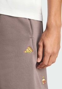 Šedé bavlnené šortky s malými vyšívanými vzormi pizze a nápoja na prednej strane. Majú bočnú kapsu a elastický pás.